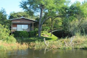 a cabin next to a river with a bridge at Kayube Estate Bungalows in Livingstone