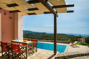 patio ze stołem i krzesłami oraz basenem w obiekcie Country Villa Atheras w mieście Athéras