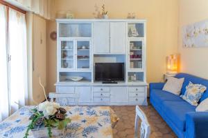a living room with a blue couch and a tv at Eveten Apartments - Diano Marina in Diano Marina