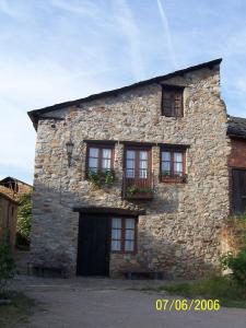 ein Steingebäude mit Fenstern und Blumen darauf in der Unterkunft Las Medulas Los Telares in Las Médulas