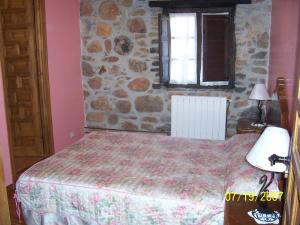 ein Schlafzimmer mit einem Bett und einer Steinmauer in der Unterkunft Las Medulas Los Telares in Las Médulas