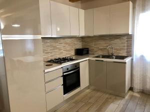 a kitchen with white cabinets and a stove and a sink at Casa Sophy in Chioggia