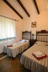 2 letti in una camera con tende bianche di Tu Villa Rural Acequia 5 Dormitorios ad Alhaurín el Grande