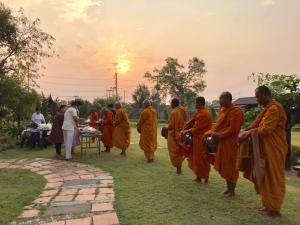 a group of monks in orange robes walking in the grass at Rueanrubkwan in Ang Thong