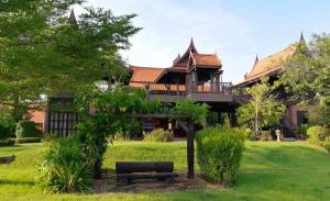 a large house with a bench in the yard at Rueanrubkwan in Ang Thong