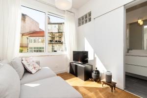 a white living room with a couch and a tv at Claude Homes Lisbon Marques in Lisbon