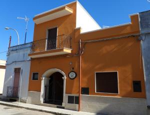 un edificio arancione e bianco con un orologio sopra di I tre feudi - Casa Vacanza ad Avetrana