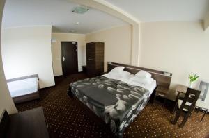 プウォツクにあるHotel Podkowaのベッドとデスクが備わるホテルルームです。