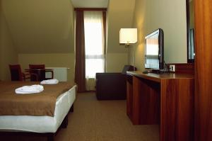a hotel room with a bed and a flat screen tv at Fiáker Panzió in Zalaszentgrót