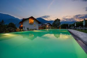 a swimming pool with a house in the background at Hotel Neuhausmühle in Vilpiano