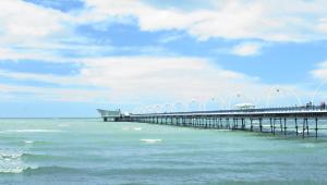 a pier stretches out over the ocean on a cloudy day at Westcliffe Apartments in Southport