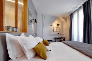 - une chambre avec un lit blanc et des oreillers jaunes dans l'établissement Tinah Paris, Réaumur - Montorgeuil, à Paris