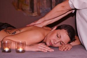 Un uomo a torso nudo che si fa fare un massaggio alla schiena da un uomo di Maison Sous Le Pont a Meyras