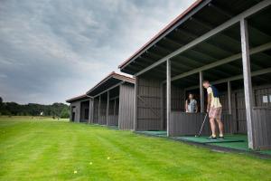a man is playing golf in front of a building at National Golf Resort in Klaipėda