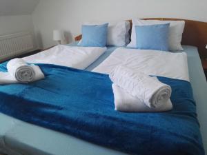 two beds with blue and white sheets and towels at Hotel Jestřábí in Černá v Pošumaví