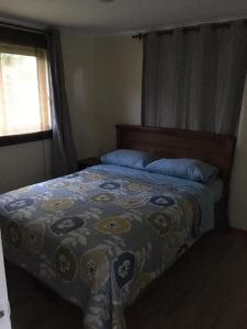 um quarto com uma cama com um cobertor e uma janela em Los Pinos de Quilvo em Romeral