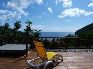 a yellow chair sitting on a deck with the ocean at villa marguerita in Deshaies