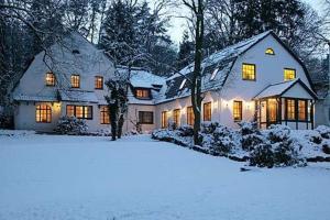 una casa cubierta de nieve con sus luces encendidas en Hotel Buchenhof, en Worpswede