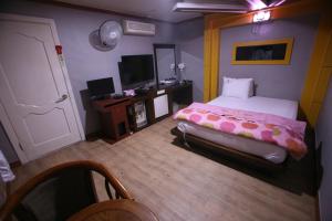 K Motel في دايغو: غرفة نوم بسرير ومكتب وتلفزيون