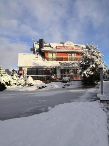 a building in front of a snow covered building at Motelis Smagratis in Kretinga