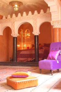 - une chambre avec un lit et une chaise violette dans l'établissement Riad Fatinat Marrakech, à Marrakech