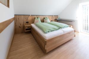 a bedroom with a wooden bed with green pillows at Gasthaus - Gästehaus Schusterbauer in Rein