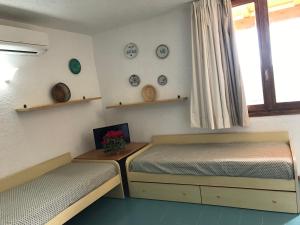 Un dormitorio con 2 camas y una ventana con platos. en Centro Vacanze Cugnana Verde en Marina di Portisco