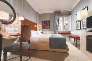 ローマにあるスタンダール ホテルのベッド、デスク、椅子が備わるホテルルームです。
