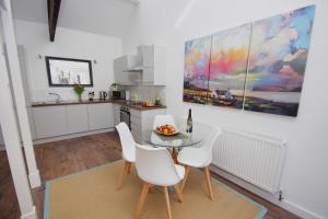 a kitchen with a glass table and white chairs at Loft Style Apartment for 4, 1 Broadhurst Court, close to town, station & hospital in Stockport