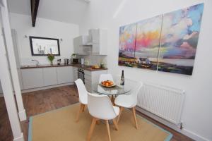 a kitchen with a glass table and white chairs at Loft Style Apartment for 4, 1 Broadhurst Court, close to town, station & hospital in Stockport +17 photos