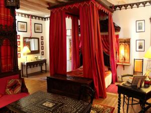 a bedroom with red curtains and a bed with a table at Château De Chambiers in Durtal