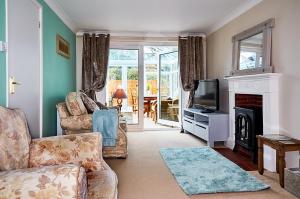uma sala de estar com um sofá, uma televisão e uma lareira em Sunshine Corner em West Mersea