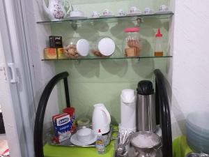 un estante con tazas y platos en una mesa en Pousada Nascimentos en Bertioga