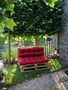 eine rote Couch unter einem Baum im Garten in der Unterkunft Gîte de Corbion in Leignon
