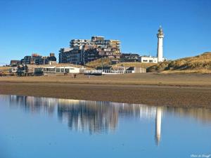 a view of a beach with a lighthouse and buildings at Beach-house27 in Egmond aan Zee