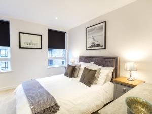 um quarto com uma cama e duas janelas em 2 Bed Property Close to Heathrow Airport em Hounslow