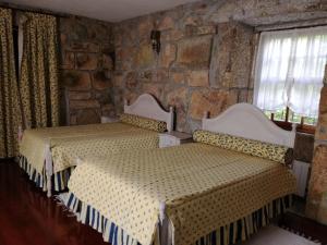 2 camas en un dormitorio con pared de piedra en Casa da Costeira, en Figueiró