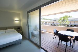 sypialnia z łóżkiem oraz balkon ze stołem i krzesłami w obiekcie Costa Nera w mieście Porto-Vecchio