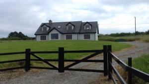 a house with a fence in front of a field at Orchard lodge Bantry in Glanbannoo Upper