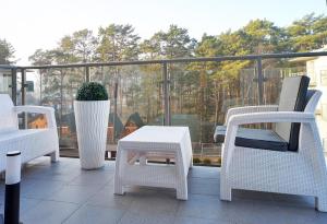 a group of chairs and a table on a balcony at Sea Apartment Leśne Tarasy in Dziwnówek