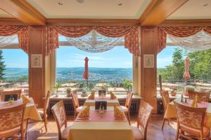 a dining room with tables and chairs and a large window at Berghotel Kockelsberg in Trier