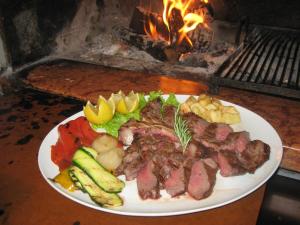 a plate of meat and vegetables in front of a grill at HOTEL BUCA DI BACCO in Volta Mantovana