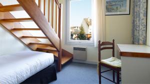 ベノデにあるLes Bains de Mer Riviera Bretonneの階段とベッド、窓が備わる客室です。