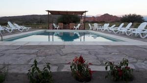 a swimming pool with white chairs and a gazebo at Hotel Castillos de Cafayate in Cafayate
