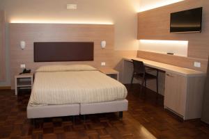 a bedroom with a bed and a desk with a television at HOTEL BUCA DI BACCO in Volta Mantovana