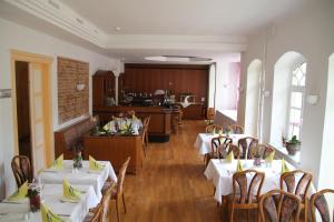 a restaurant with white tables and chairs and a kitchen at Villa Wilisch in Amtsberg