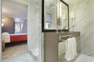 un bagno con lavandino, specchio e letto di Hotel Concortel Paris a Parigi