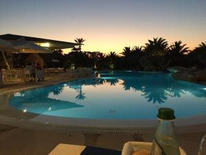 ein großer Pool mit Sonnenuntergang im Hintergrund in der Unterkunft Cupola Bianca Resort in Lampedusa
