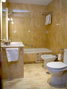 y baño con aseo, lavabo y bañera. en Apartamentos Miguel Angel, en Estepona