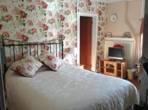 a bedroom with a bed with floral wallpaper at Westcourt Farm in Shorwell